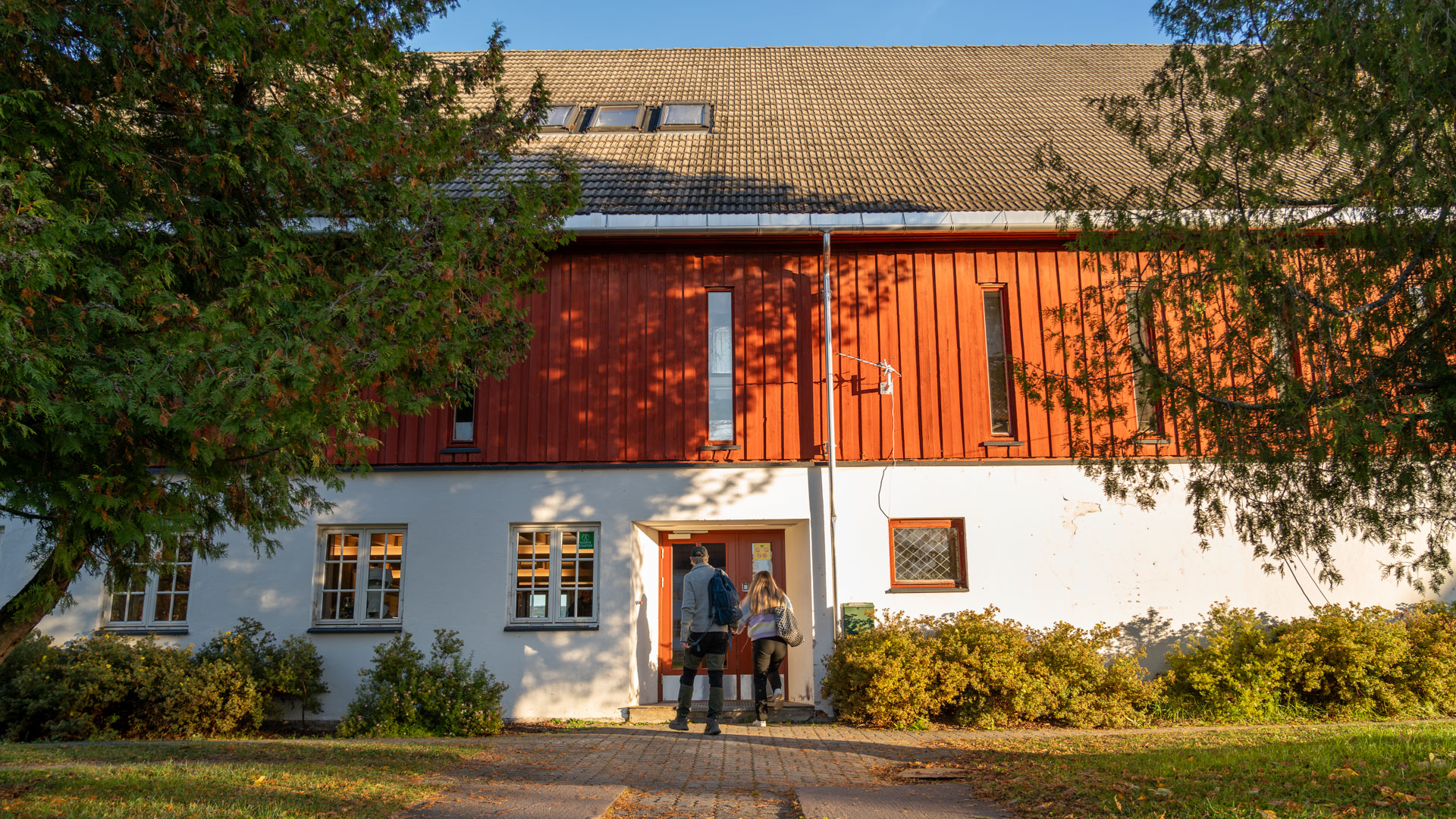 Studenter går inn i det rødmalte fjøset.