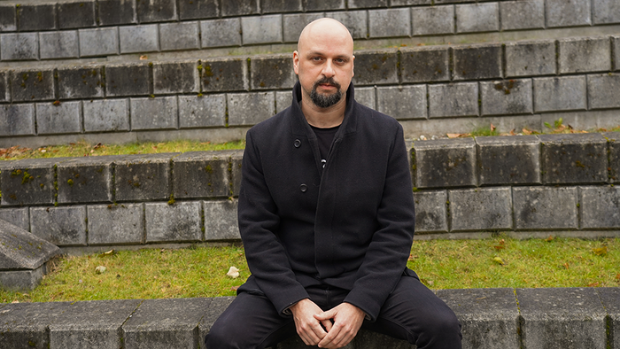 Nadim Khoury sitter på en mur, ser i kamera