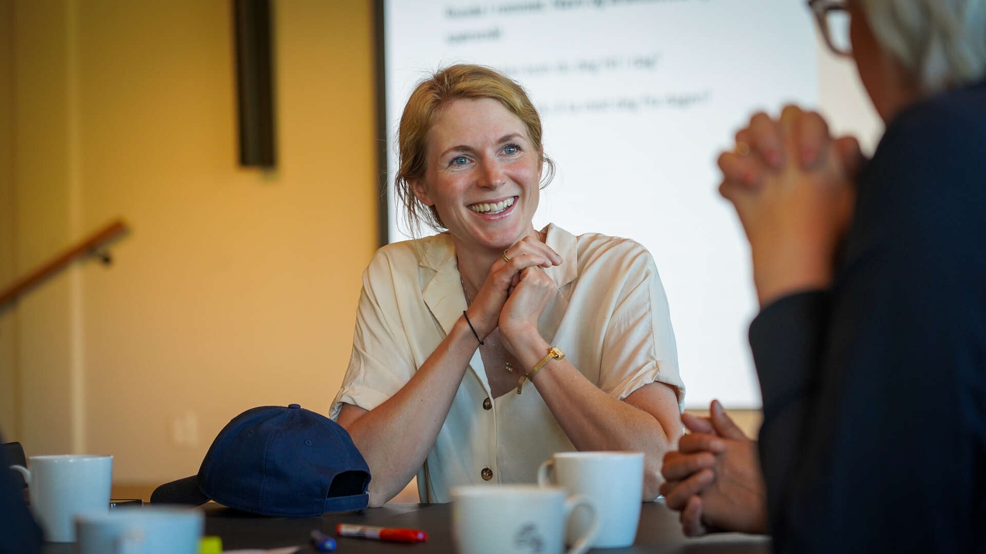 Dame ser smilende på en annen person ved et bord