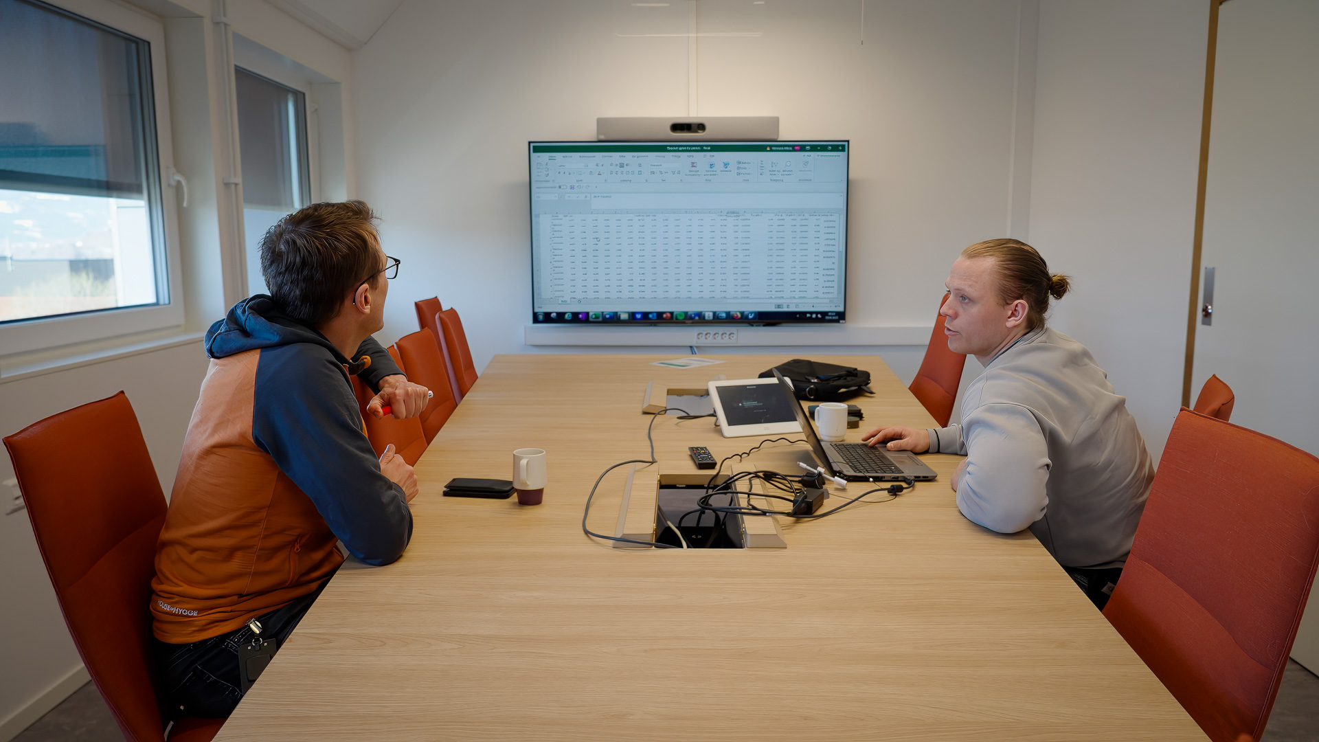 Bent og Herman sitter mot hverandre ved et langbord i et møterom.