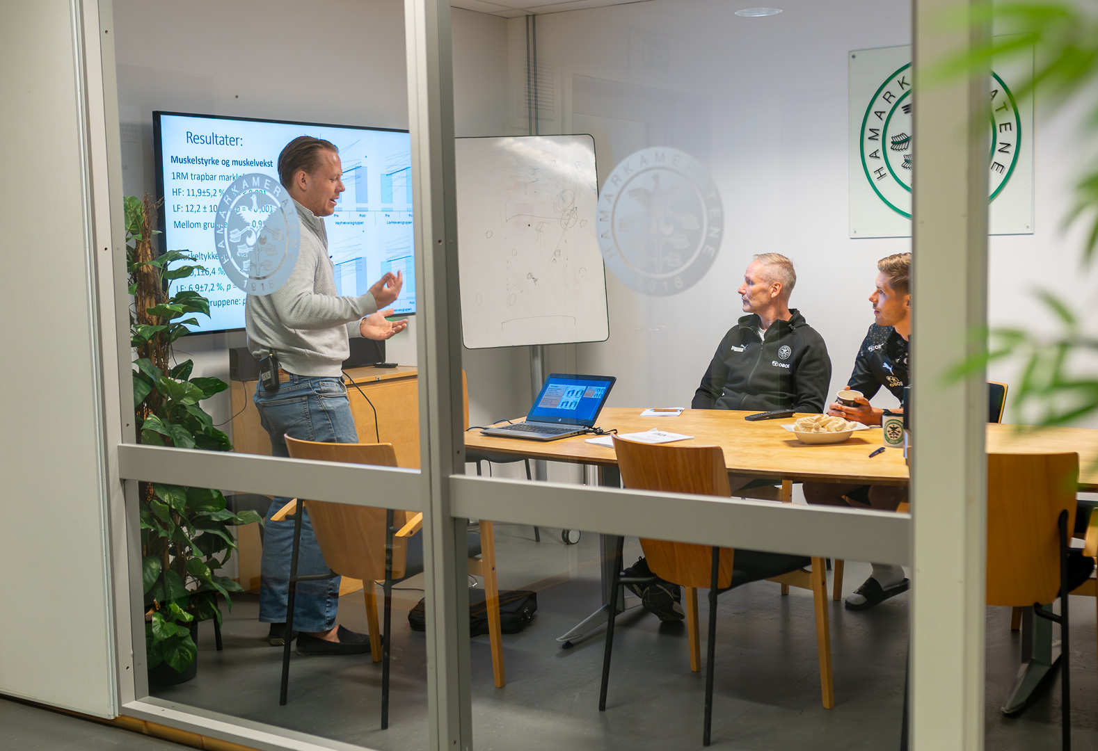 Bildet tatt gjennom vindu inn til et møterom der resultatene presenteres.