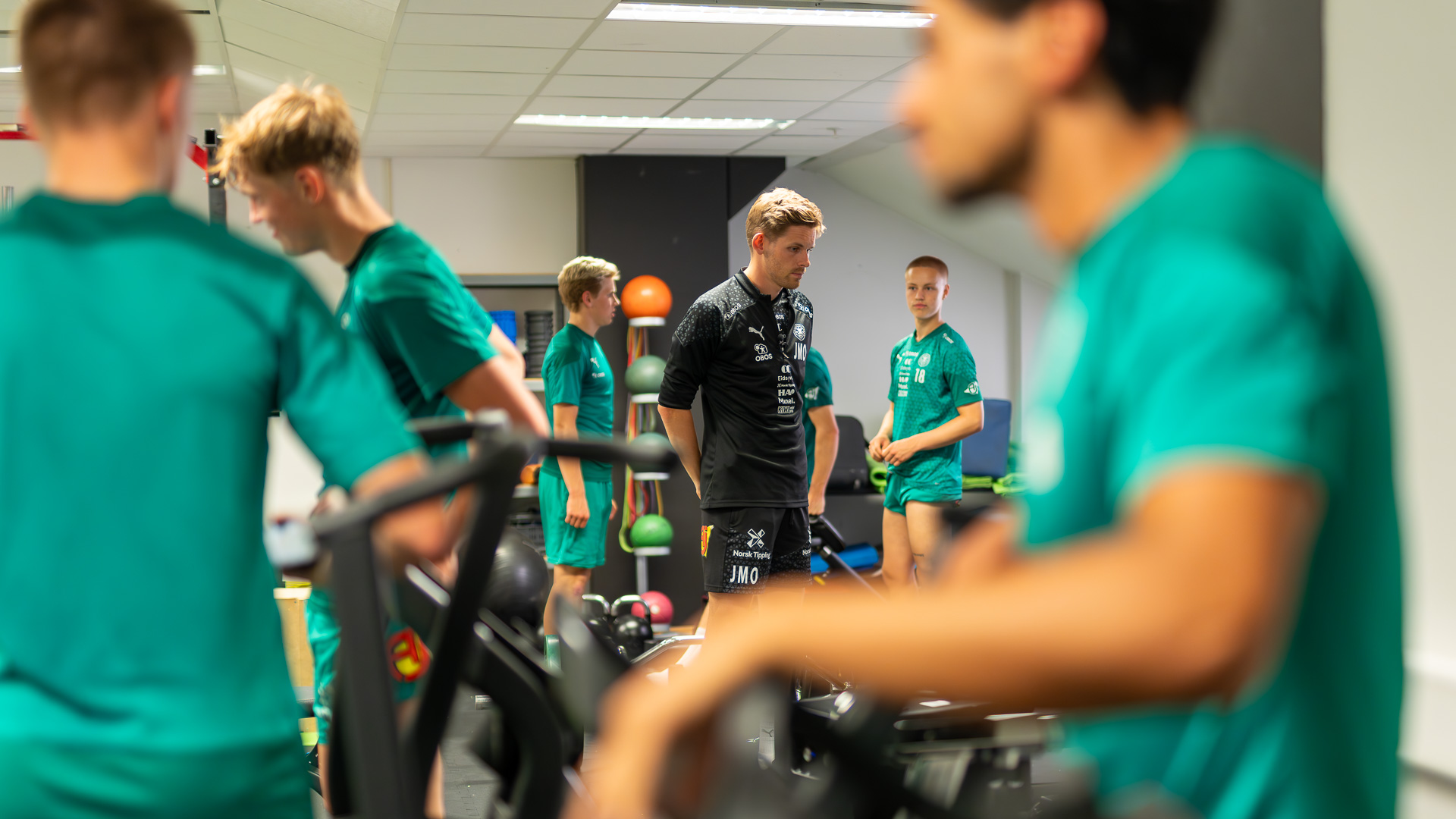 Grønnkledde fotballspiller i treningsrom.