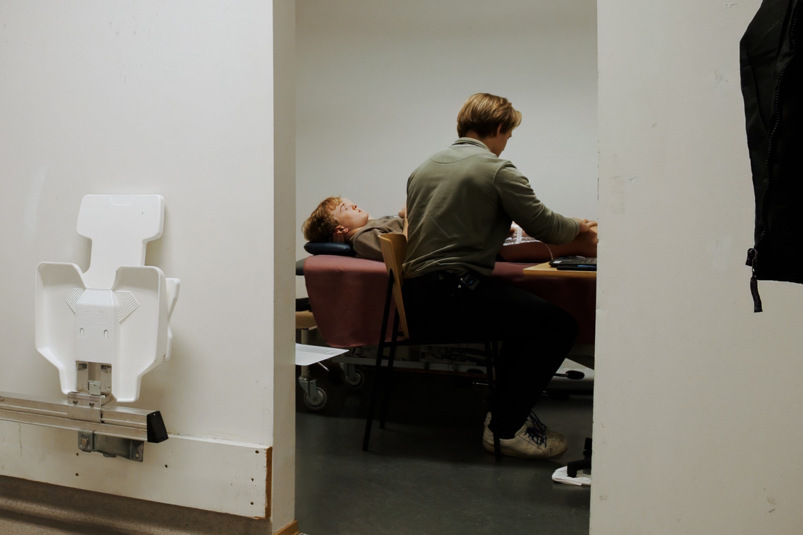 På avstand ser man spiller liggende på benk mens det tas ultralyd av muskler.