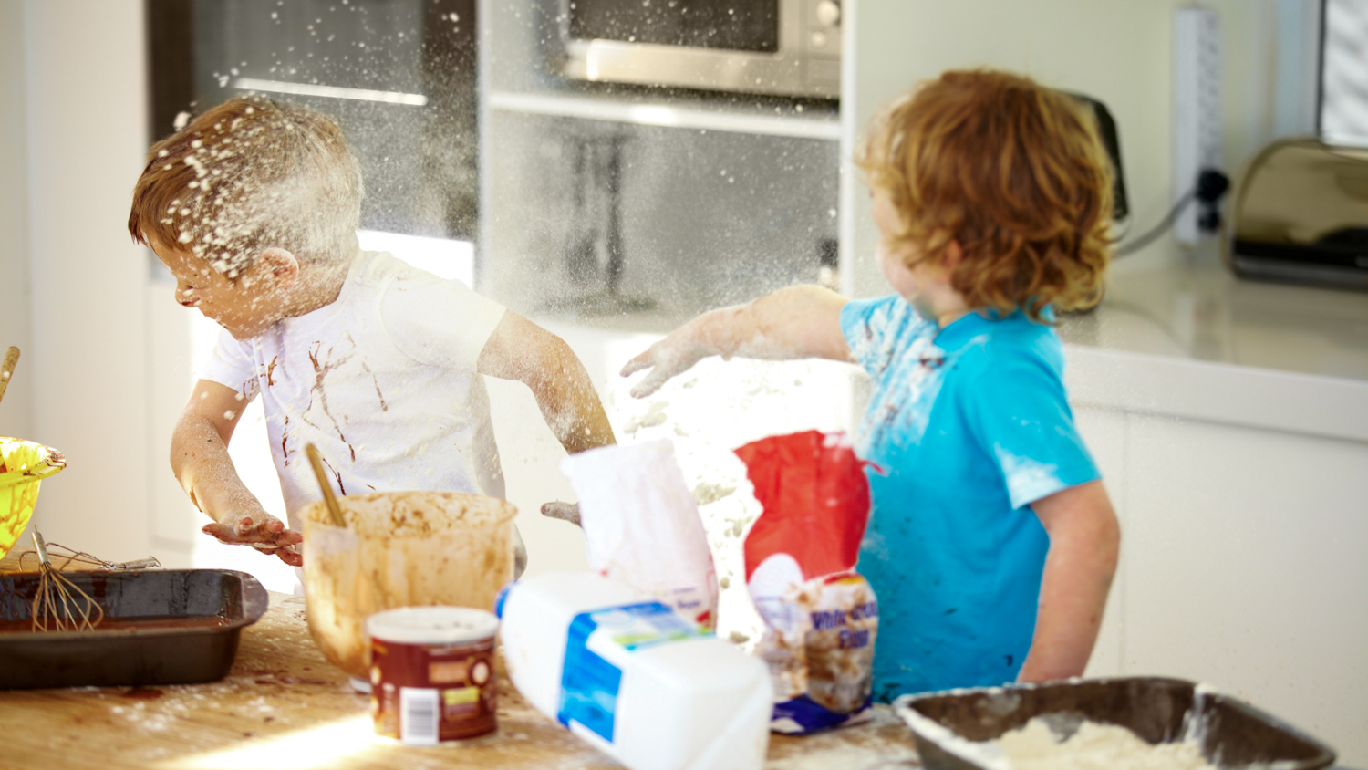 To små gutter som baker kaster mel på hverandre