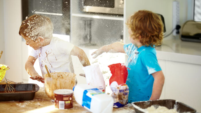 To små gutter som baker kaster mel på hverandre