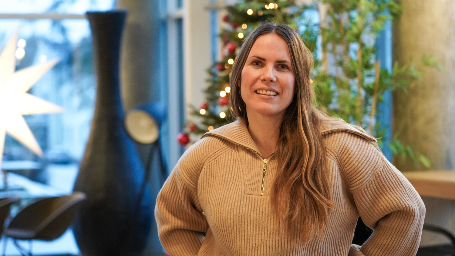 Karin Boson med ullgenser foran et juletre og en stor julestjerne som henger i et vindu