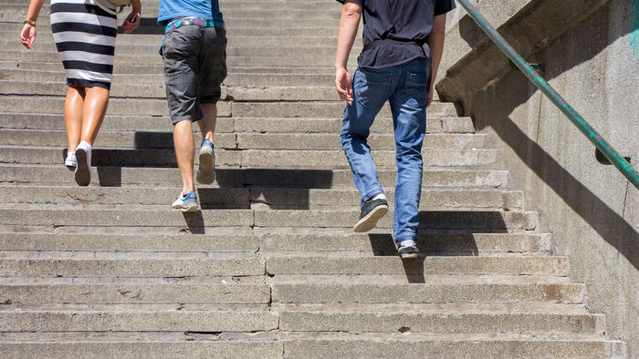 Bilde av føttene til tre personer som går opp en betongtrapp