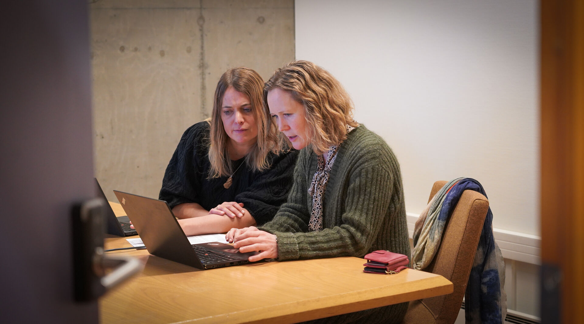 To damer sitter ved en PC og jobber