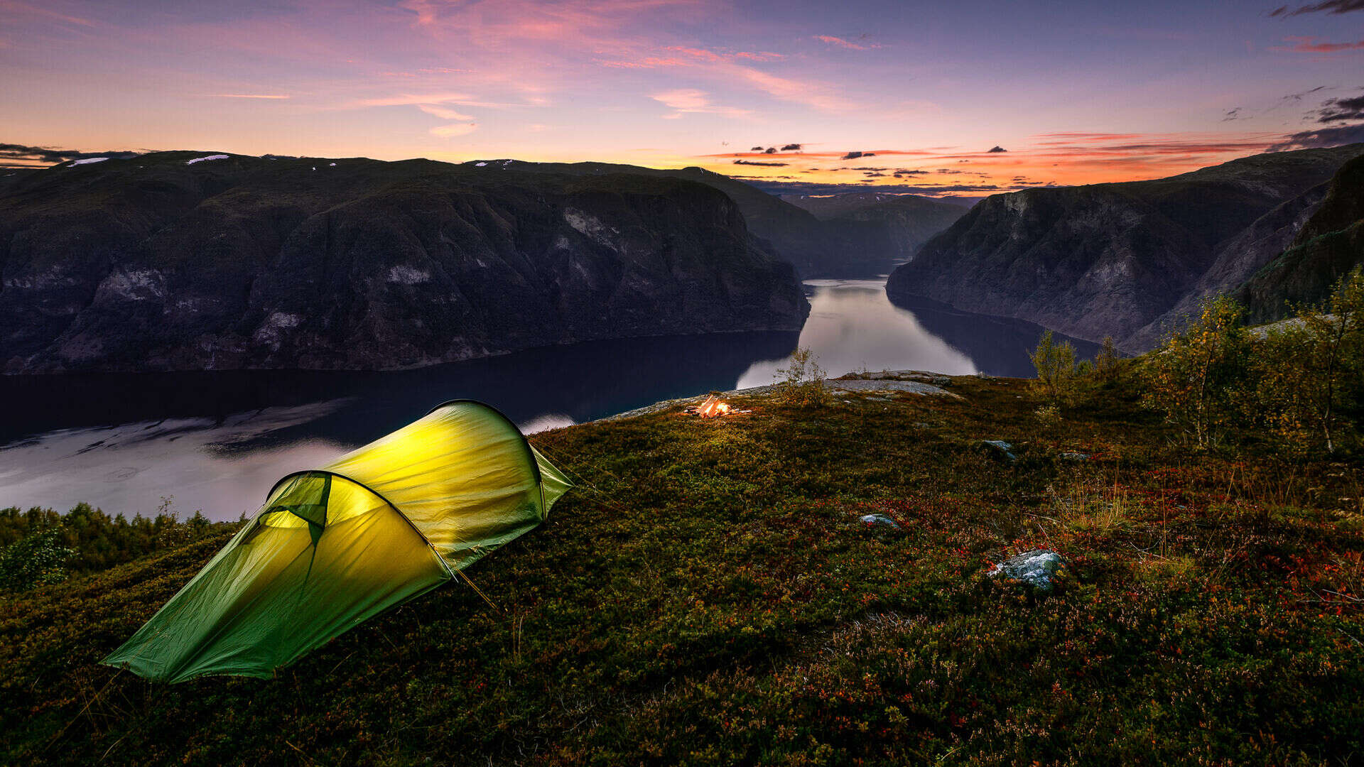 Telt i solnedgang på et fjell med utsikt til en norsk fjord