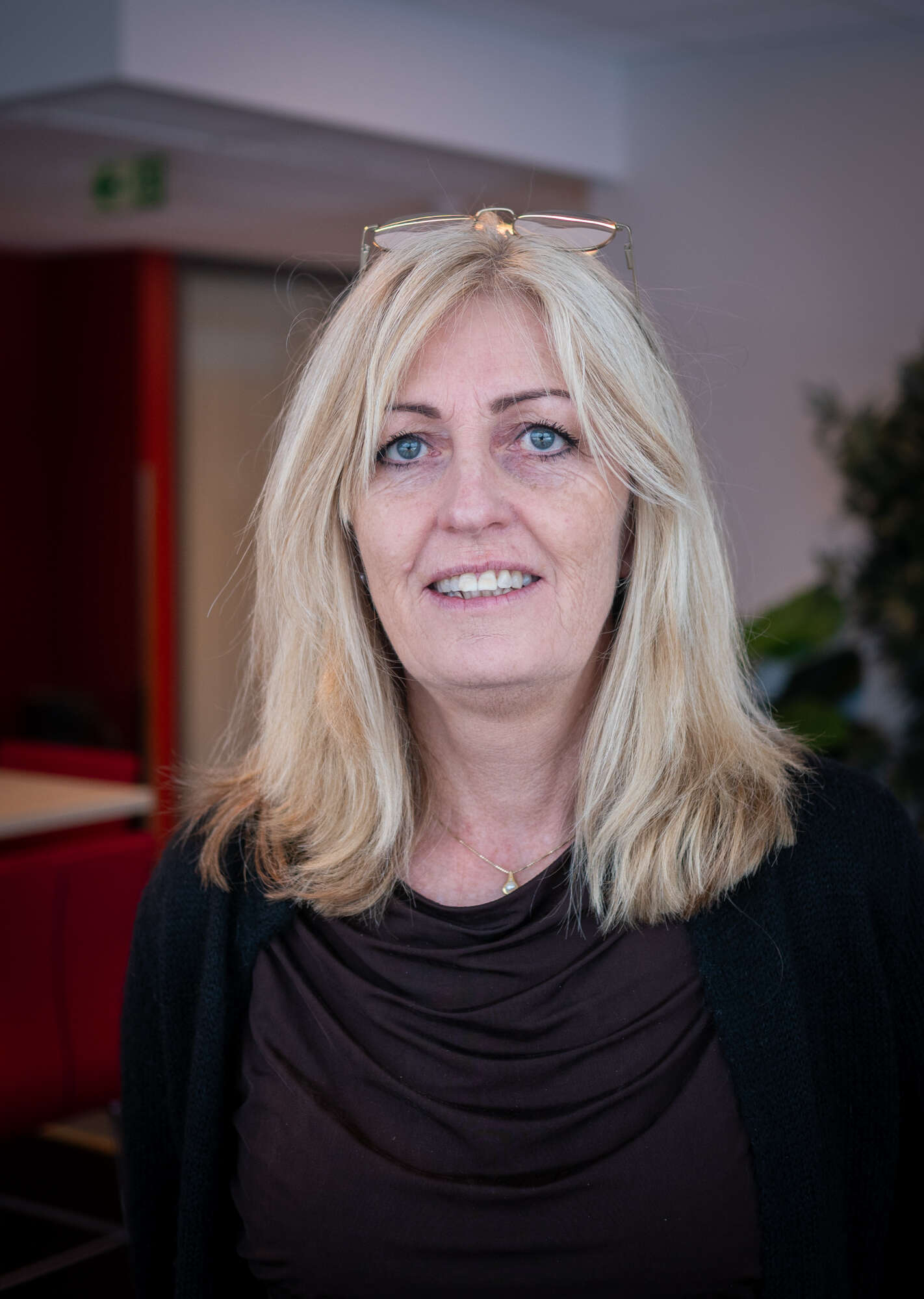 Dame med lyst hår, svart genser og briller på hodet