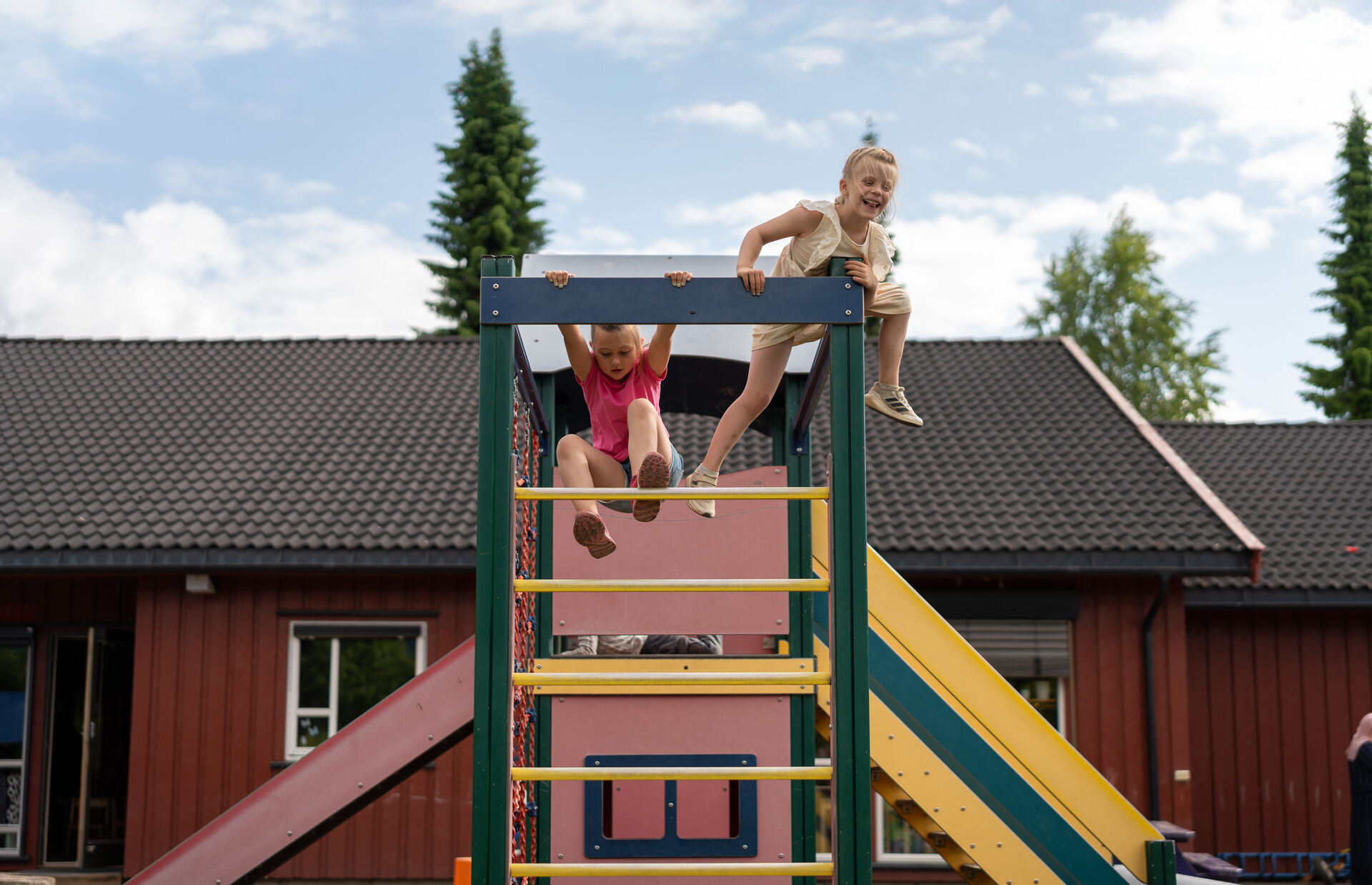 Erika og en annen jente klatrer mot toppen av et lekestativ.