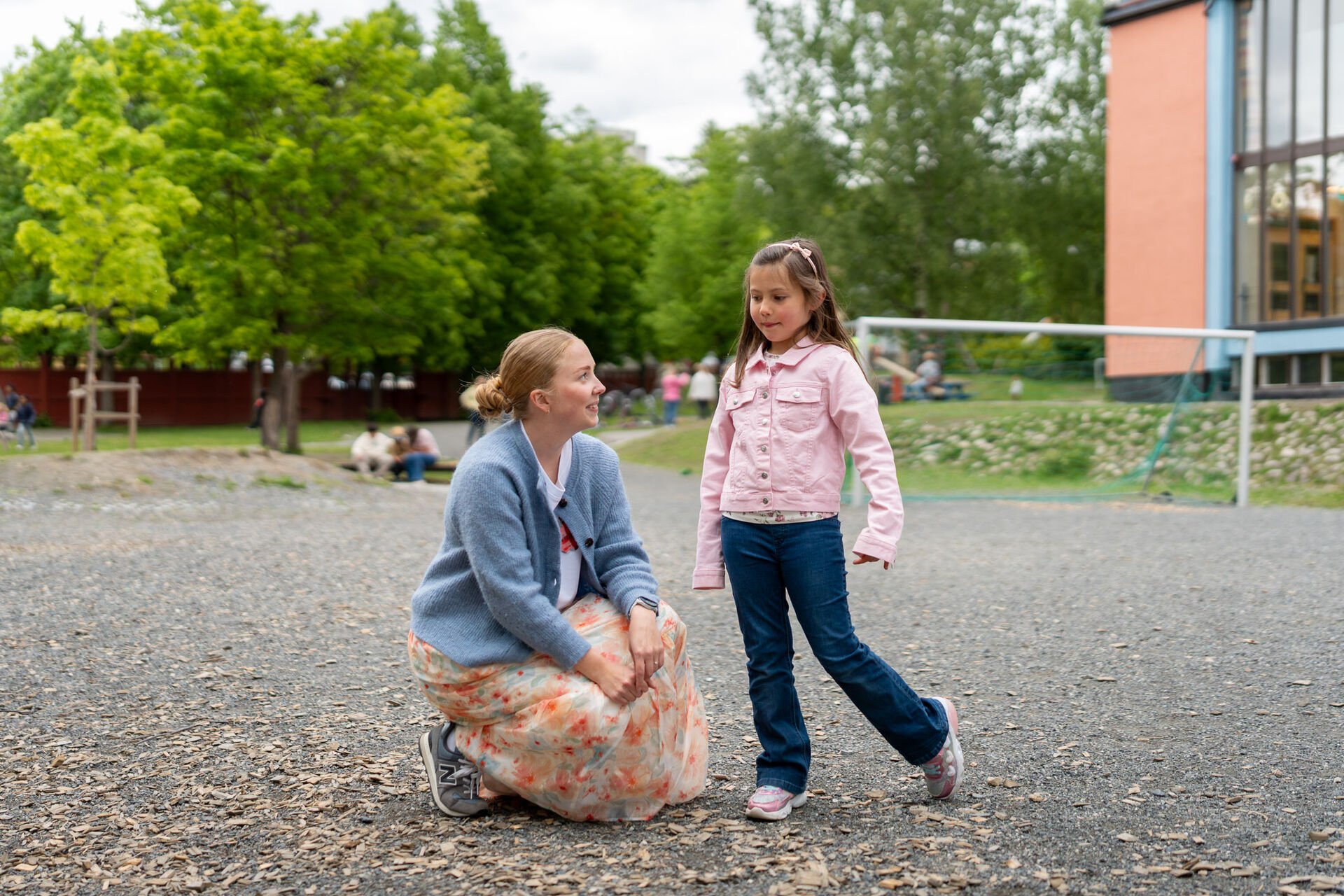 Erika i samtale med læreren sin som sitter på kne ute i skolegåreden.