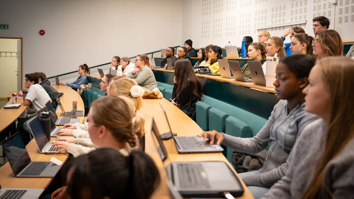 Studenter sitter i et auditorium og har forelesning