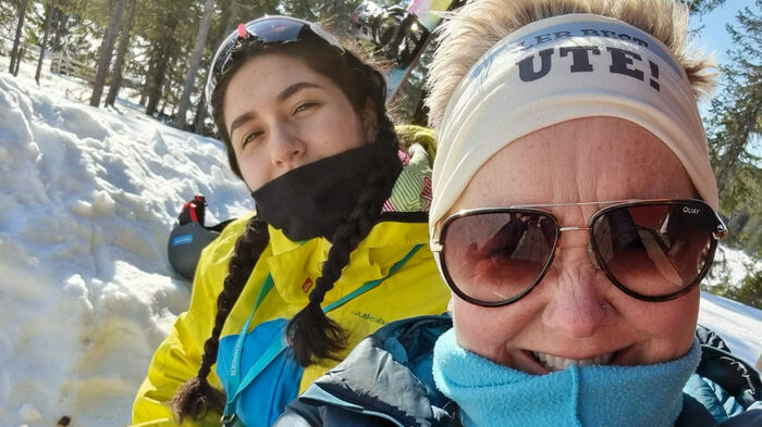 Maria og Eva-Beate i ute i solveggen med solbriller og snø i bakgrunn