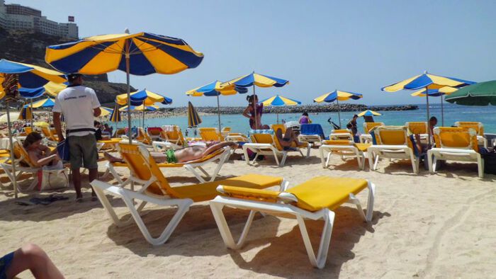 Turister på solsenger på en strand i syden