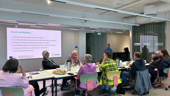 folk rundt et bord med power point esira i bakgrunn
