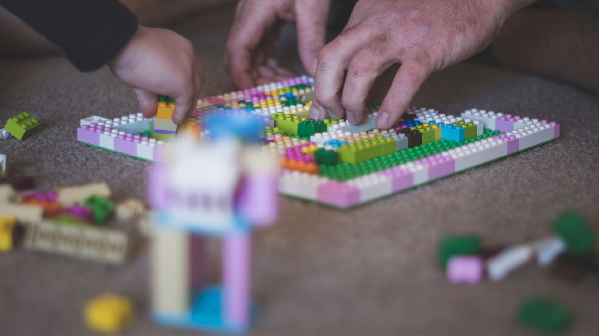 hender som bygger fargerik lego 