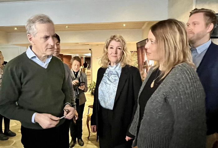 fire personer står og snakke sammen innendørs