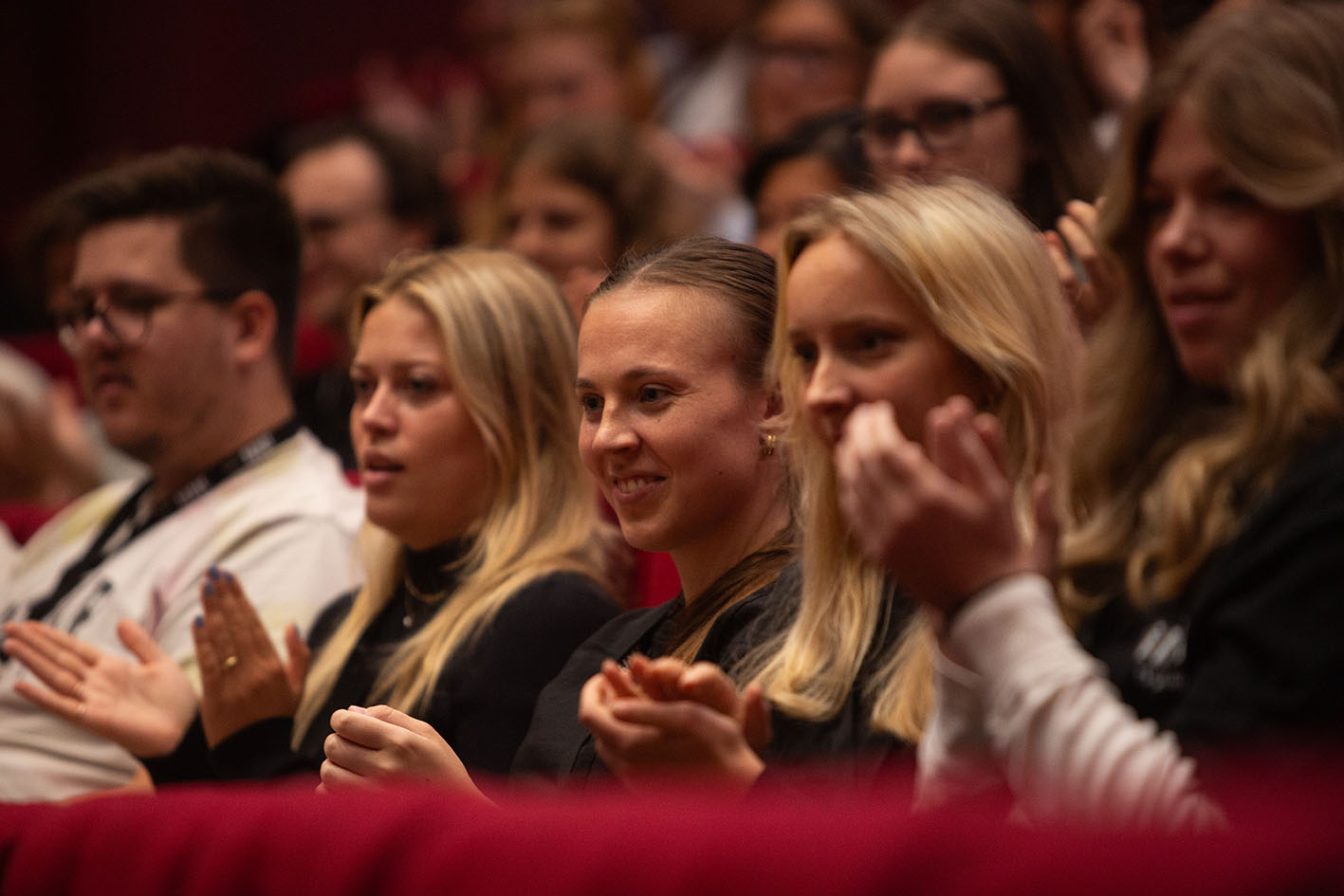 Nærbilde av studenter som smiler og klapper av et av foredragene