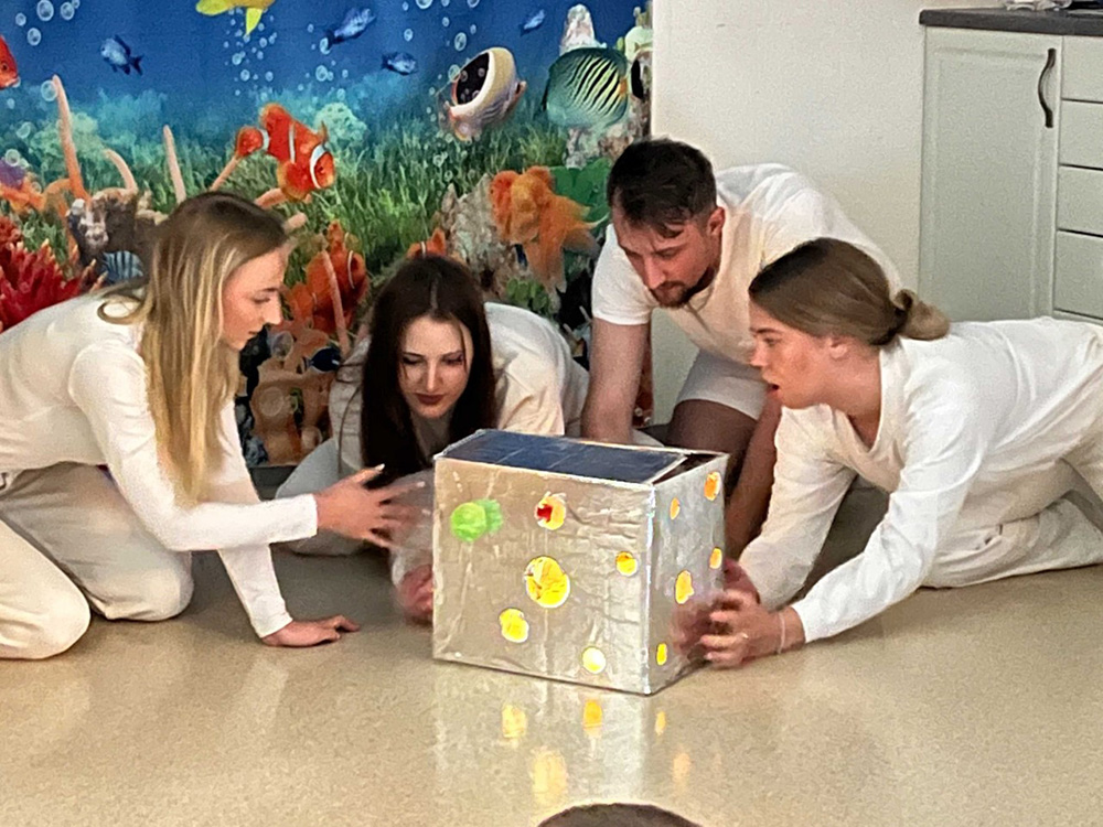 Bildet viser studenter som viser fram Den magiske boksen for barnehagebarna.