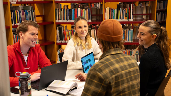Studenter som jobber sammen rundt et bord på biblioteket. 