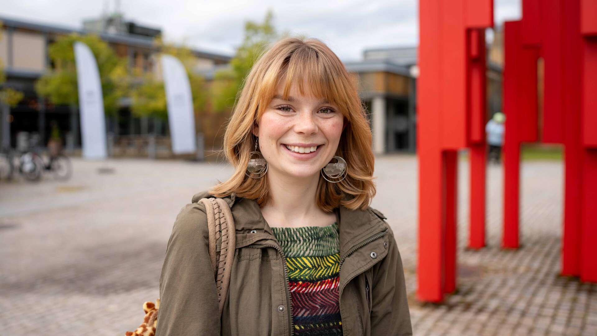 Smilende kvinne i grønn jakke under studiestart. 