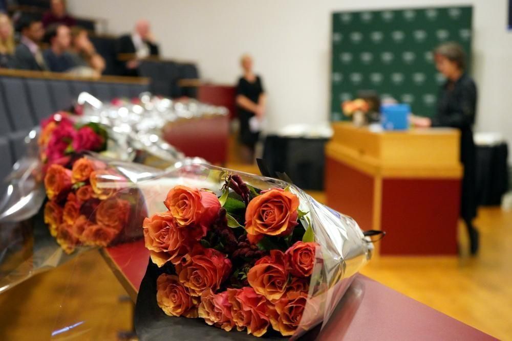 En blomsterbukett på et bord med uklare menneskeskikkelser i bakgrunnen