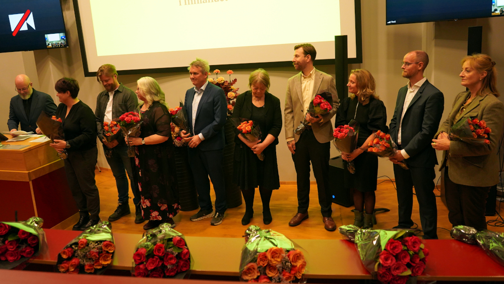 Flere personer samlet på scenen med blomster i hendene - dette er de som har fått opprykk siste året