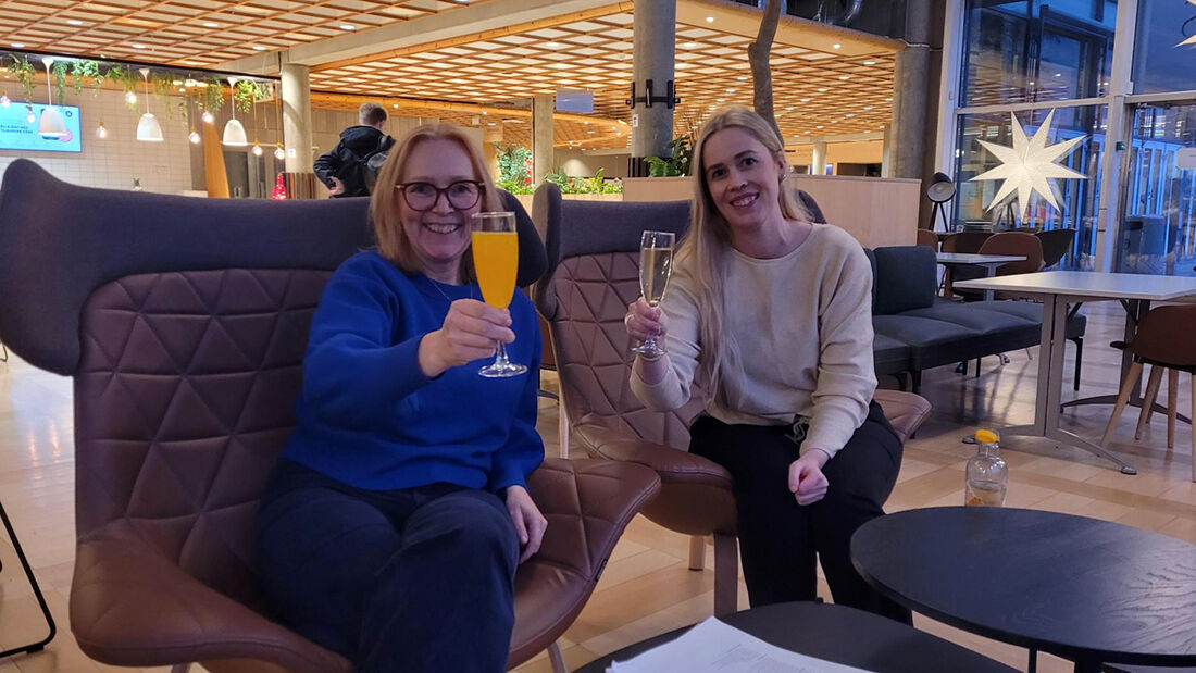 To kvinner som smiler og drikker brus. 