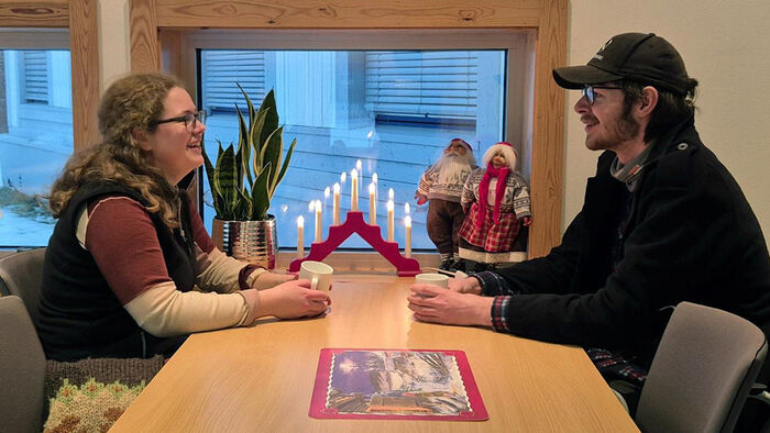 To studenter som sitter ved et bord dekket til jul. 
