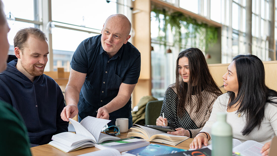 En eldre mann som bistår studenter som leser pensum. 