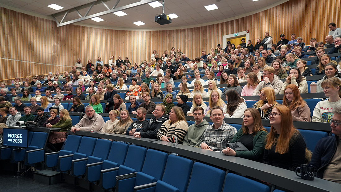 Studenter som sitter i en full forelesningssal. 