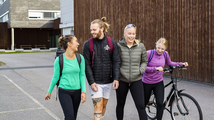 Fire blide studenter som går sammen utenfor Terningen Arena. 