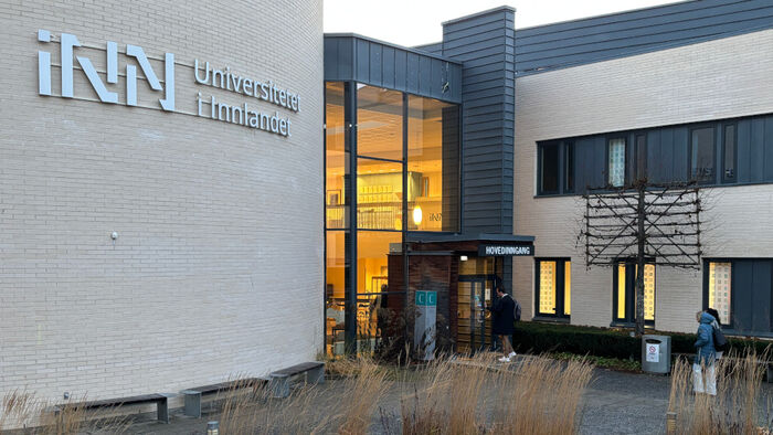 Inngangspartiet ved INNs studiested på hamar hvor tre personer er på vei inn. INNs logo henger på veggen