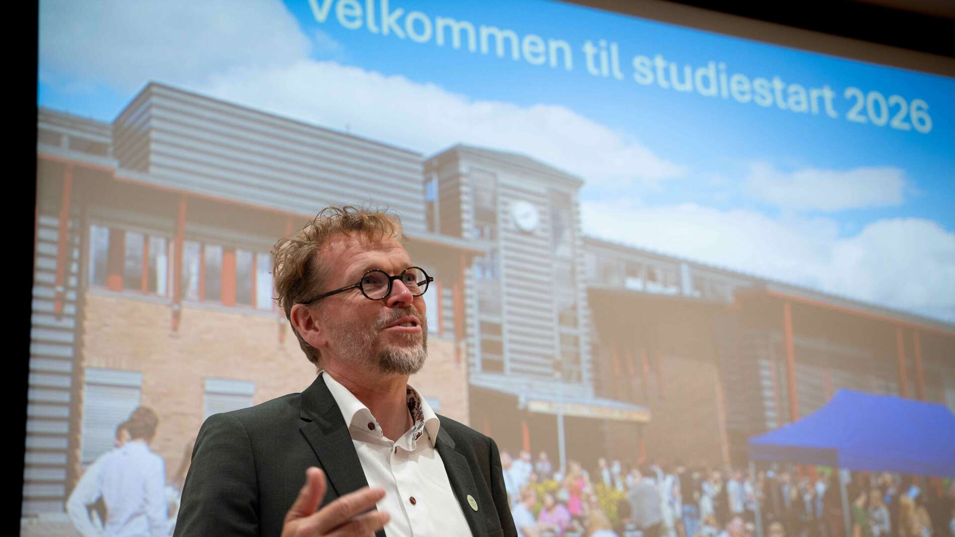 Vebjørn Horsfjor foran en skjermvisning på veggen med bilde av studiested Rena og påskriften Velkommen til studiestart 2026