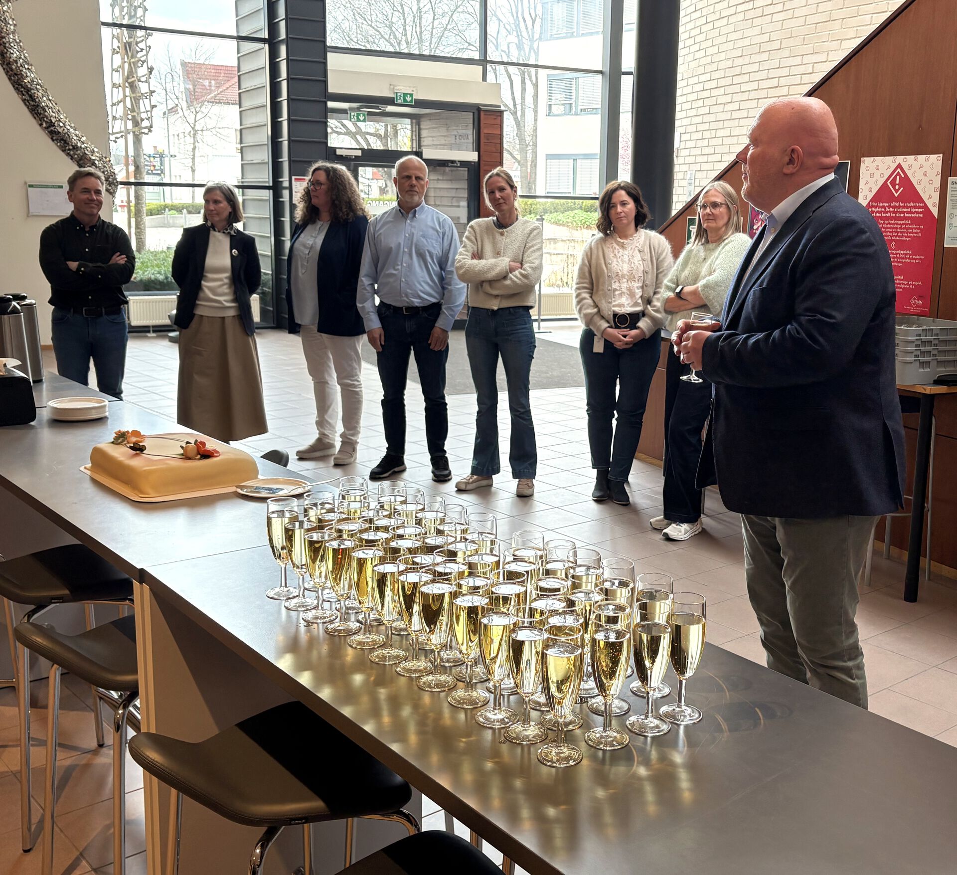 INN-kolleger står samlet for å feire med bobler og kake