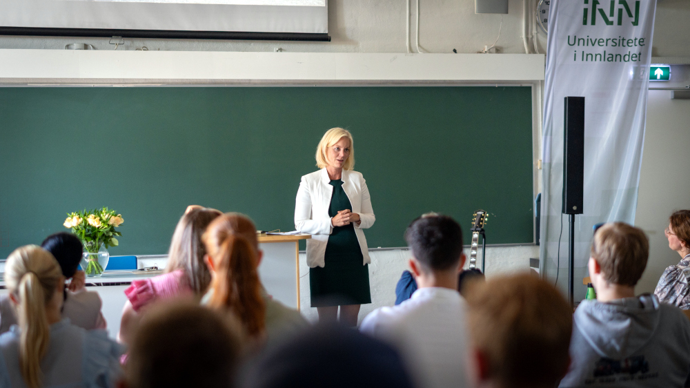 Sigrun Aasland står foran en forsamling i et klasserom