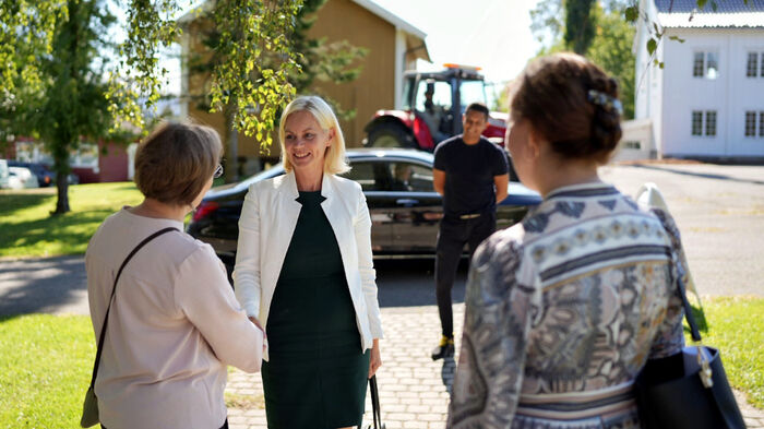 Statsråd Sigrun Aasland vendt mot kamera hilser på dekan og prorektor forskning som har ryggen vendt mot kamera