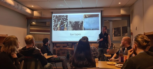 Studentene sitter på et rom og hører på hva foreleseren har å si om sikkerhet på islagte vann. I bakgrunnen vises en presentasjon på en skjerm.