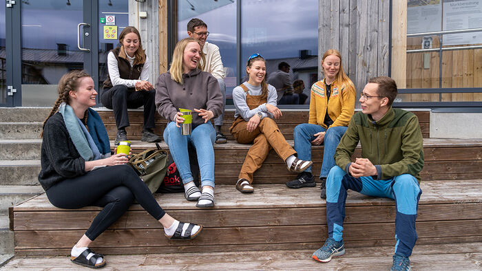 Inngangspartiet på hovedbygget på Evenstad med høstblader på bakken og stålelg i bakgrunnen. (Foto: HINN)