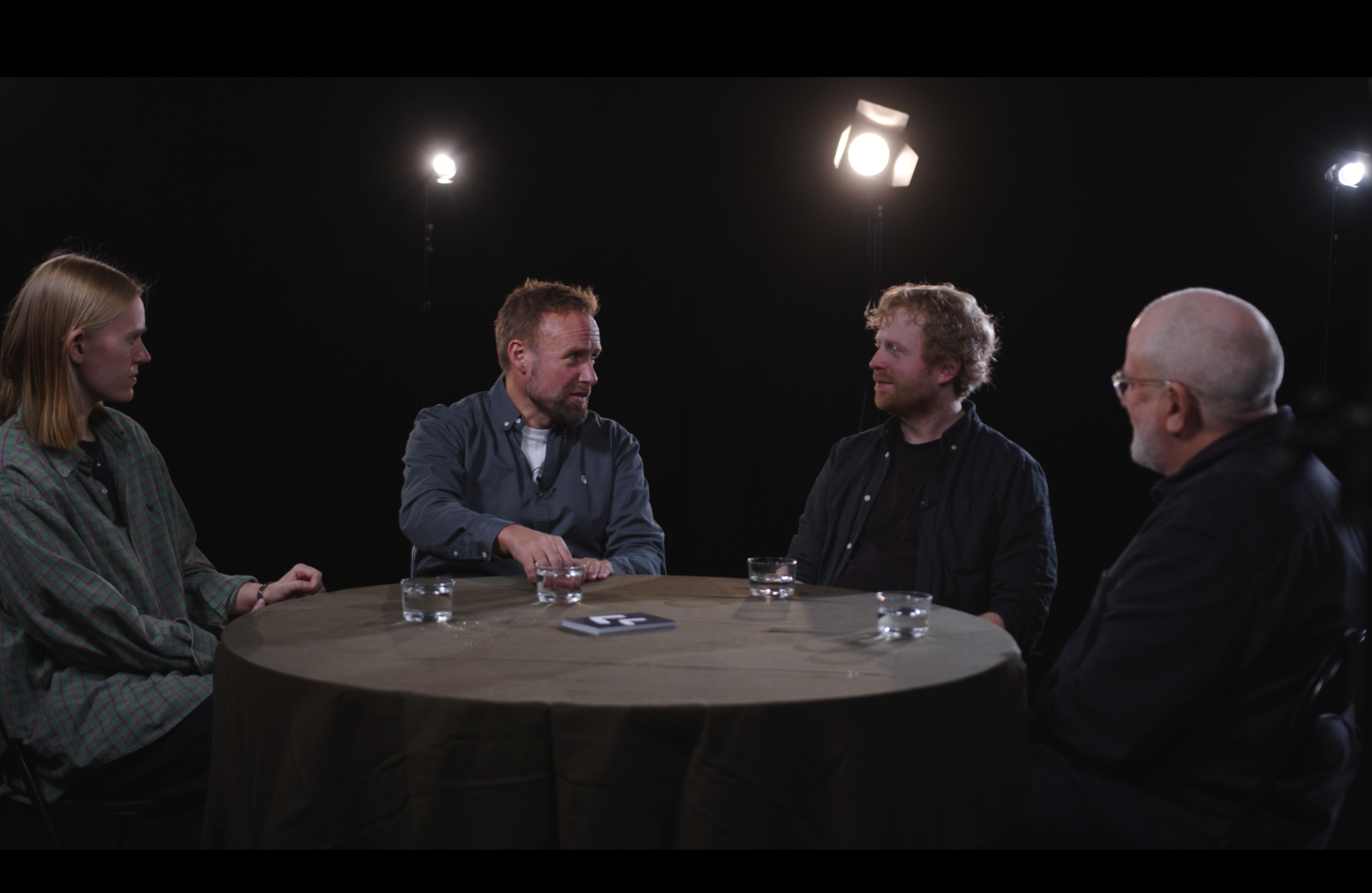 Bilde av de fire manusforfatterene  som deltar i arrangementet i samtale rundt et bord