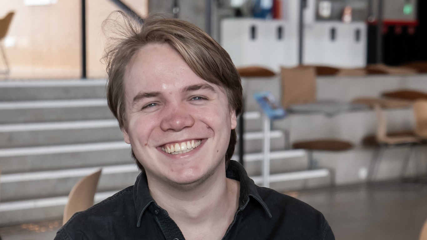 Portrett av Isak Wahl sittende ved et cafebord i svart skjorte. 