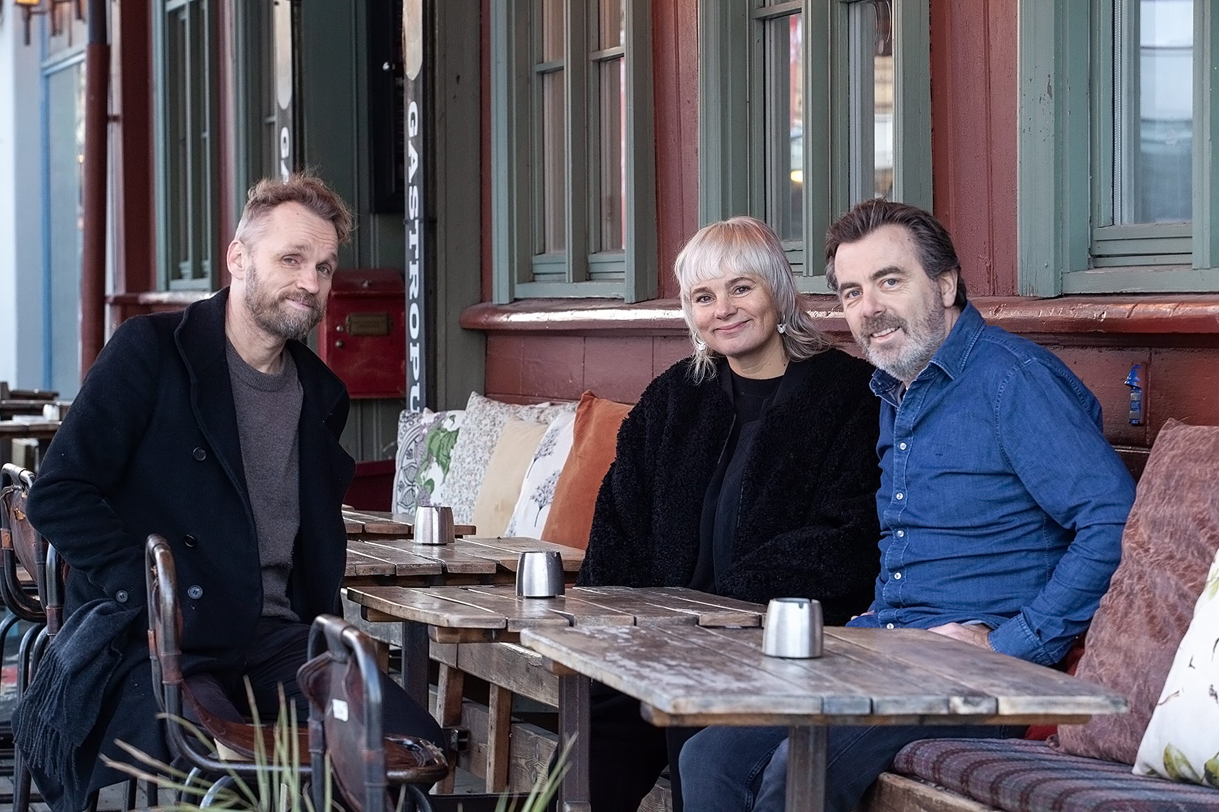 Bilde av Arild Tryggestad, Camilla Vanebo og Andreas Dreyer sittende utefor en cafe en desemberdag i 2024