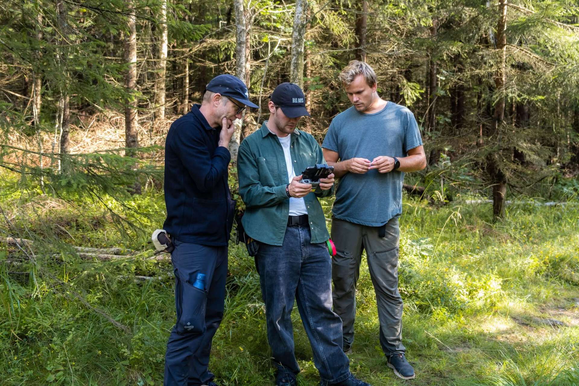 Amund i midten av to andre fotografer. Alle står ute i skogen under opptak