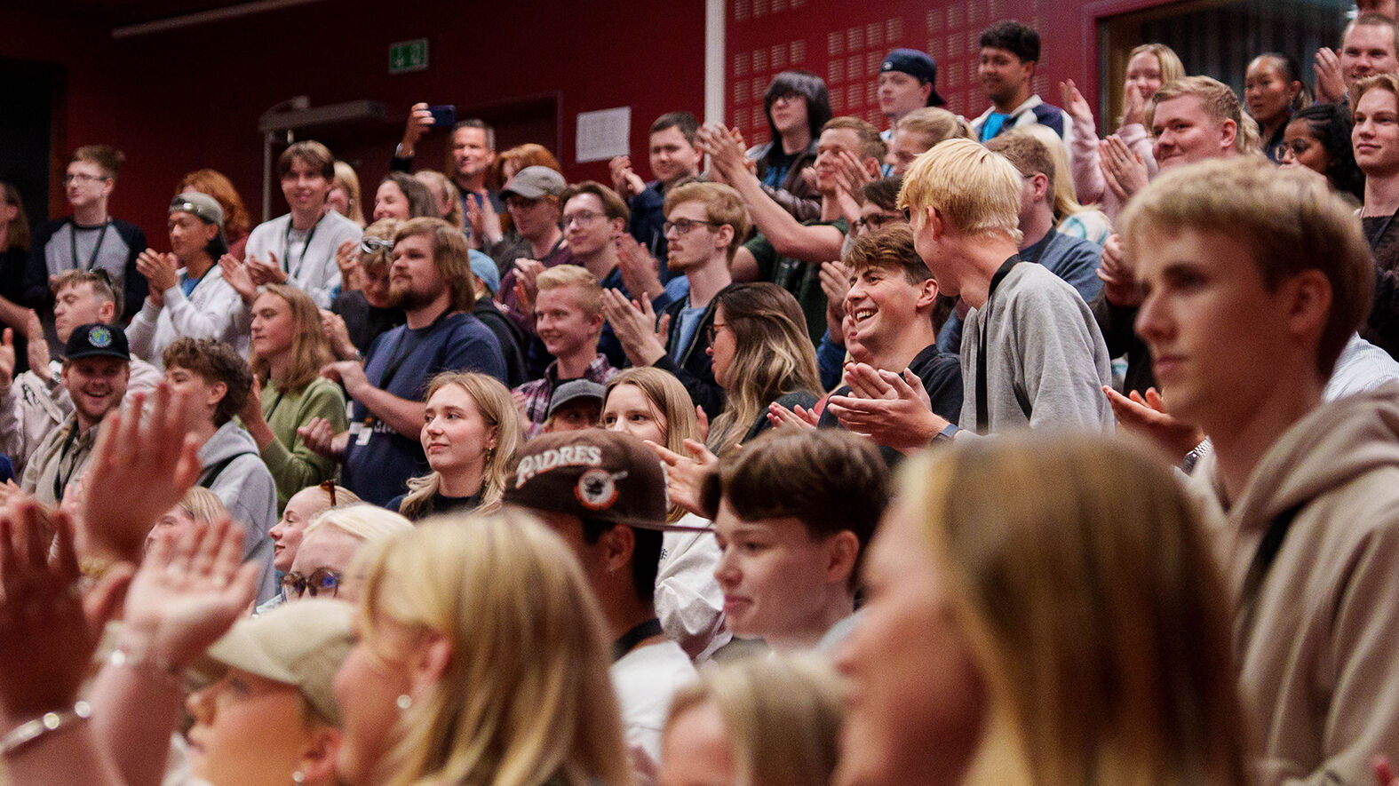 Mange studenter står samlet i et stort auditorium 