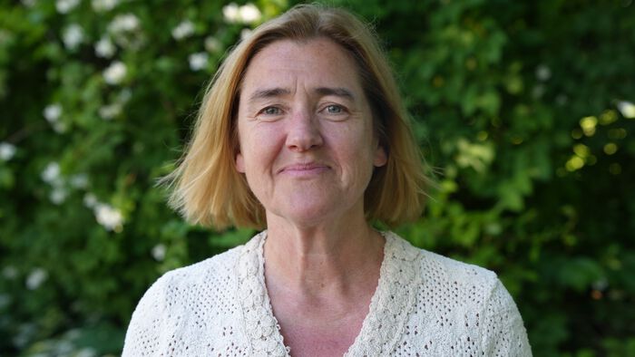 Portrettbilde av Stina Greaker med grønne vekster i bakgrunnen.