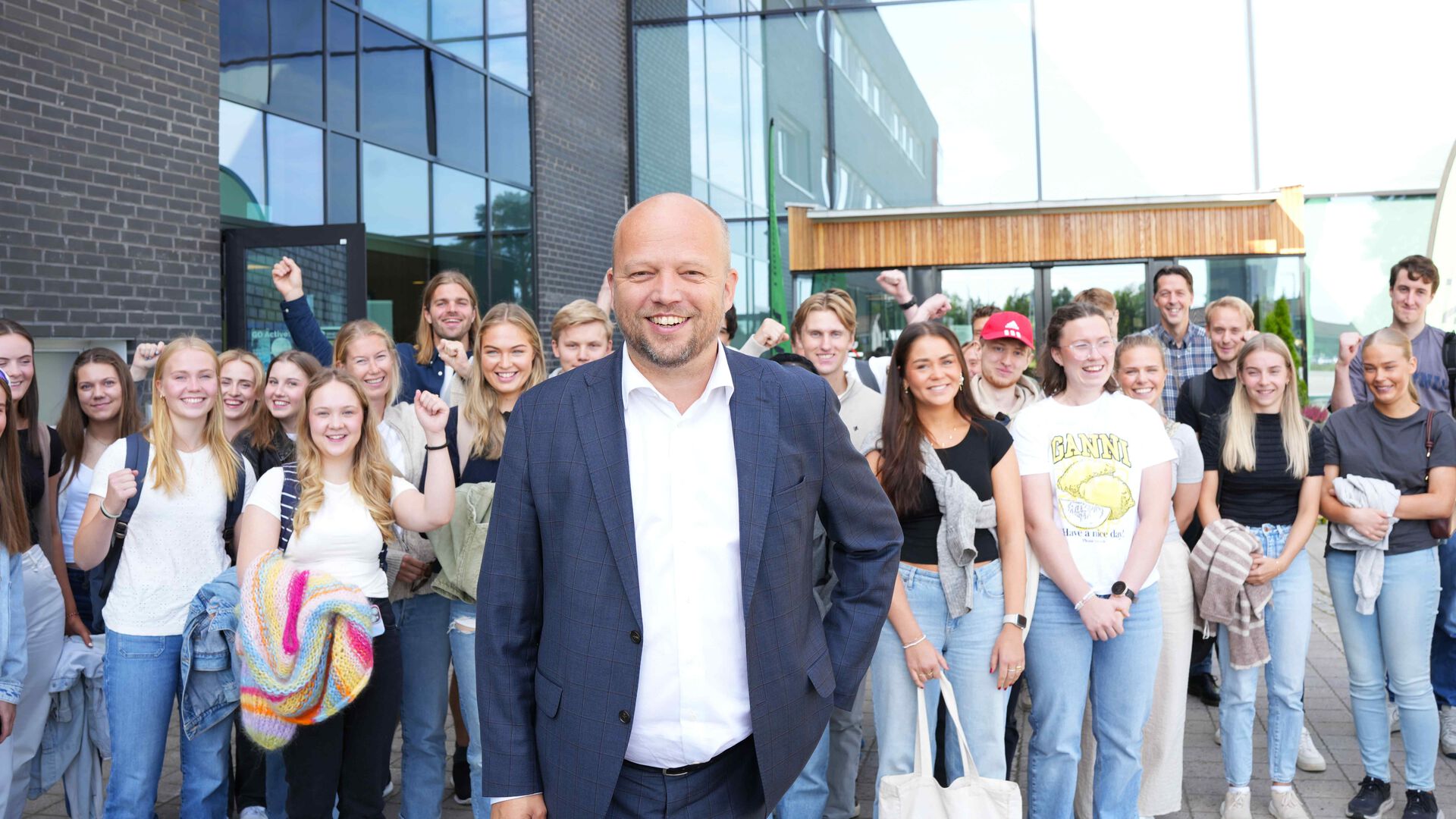 Trygve Slagsvold Vedum står foran en stor gjeng studenter utenfor hovedinngangen til høgskolen på Elverum. God stemning.