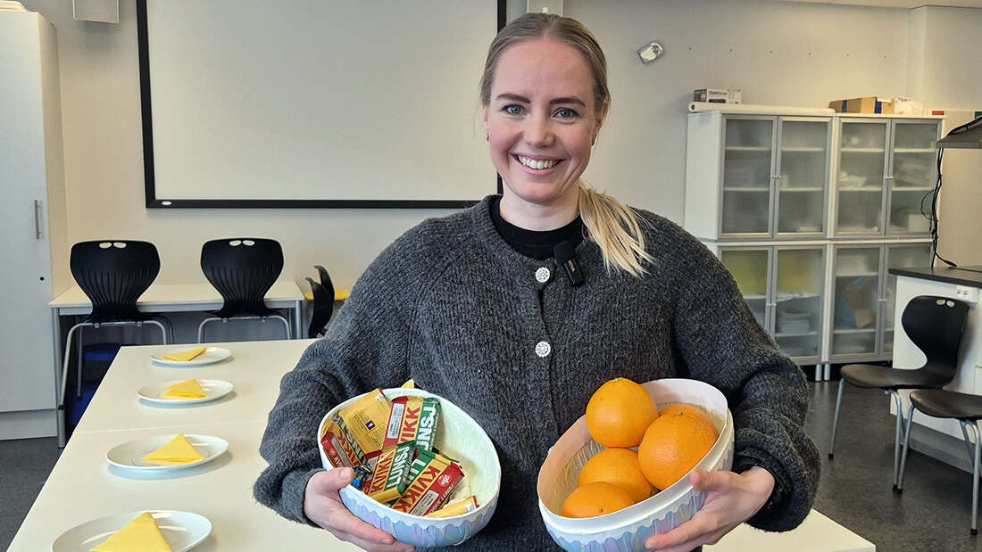 Kvinne som står med godteri og appelsiner under armen. 