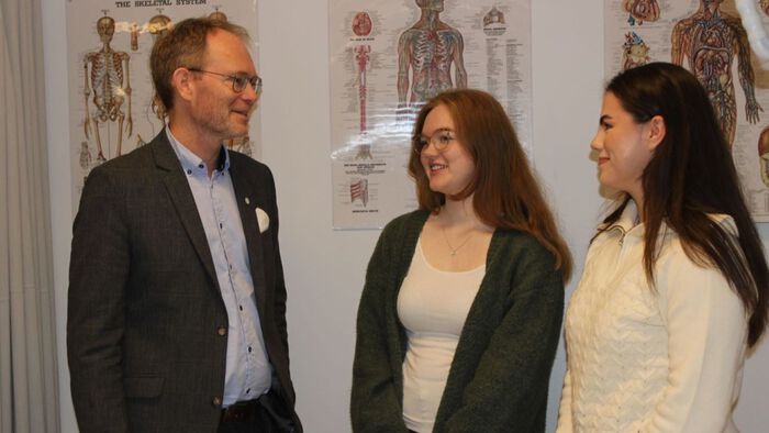 Smilende minister i hyggelig samtale med to kvinnelige studenter i sykepleierutdanningens øvingsavdelingen.
