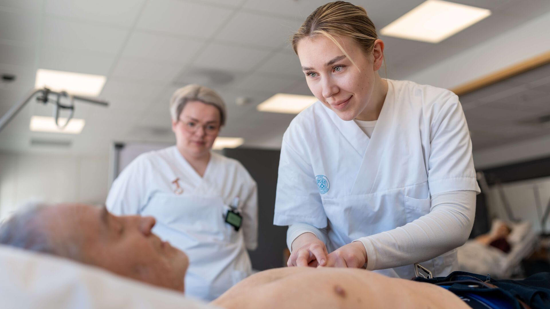 Mannlig pensjonist ligger på en benk og blir undersøkt av studenter.